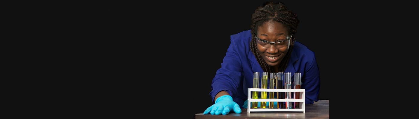 A female apprentice looks at some test tubes.